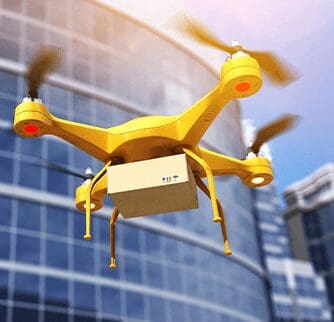 A yellow drone flying in front of a building.