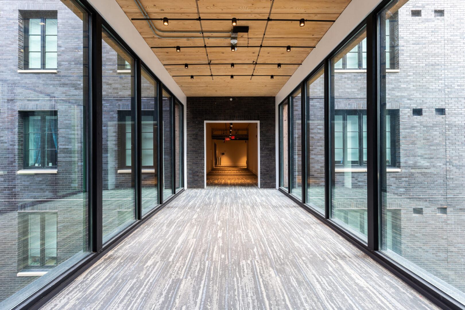 A long hallway with glass doors and wooden floors.