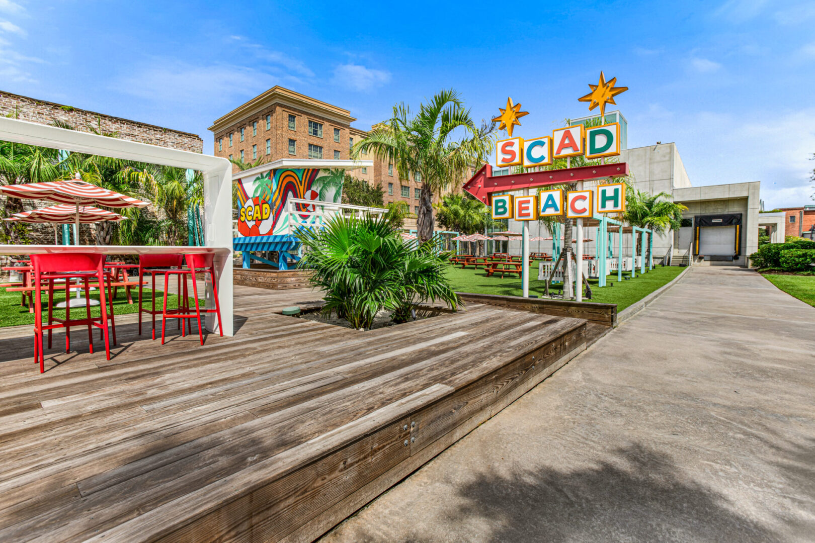 A boardwalk with palm trees and buildings in the background.