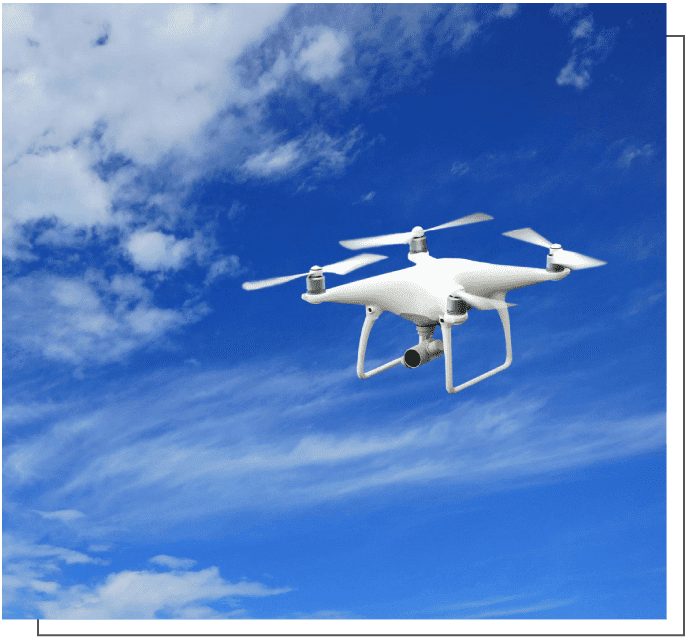 A white drone flying in the sky with clouds.