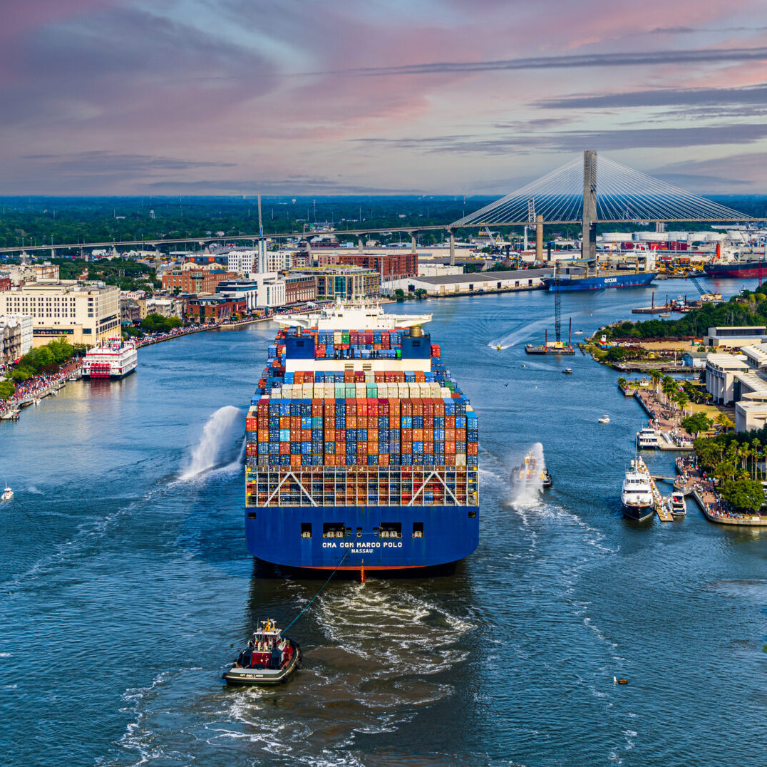 A large boat is in the water near some buildings.